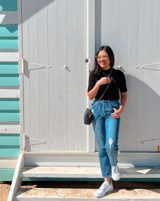 Karin smiling on a beach in front of a white beach shack